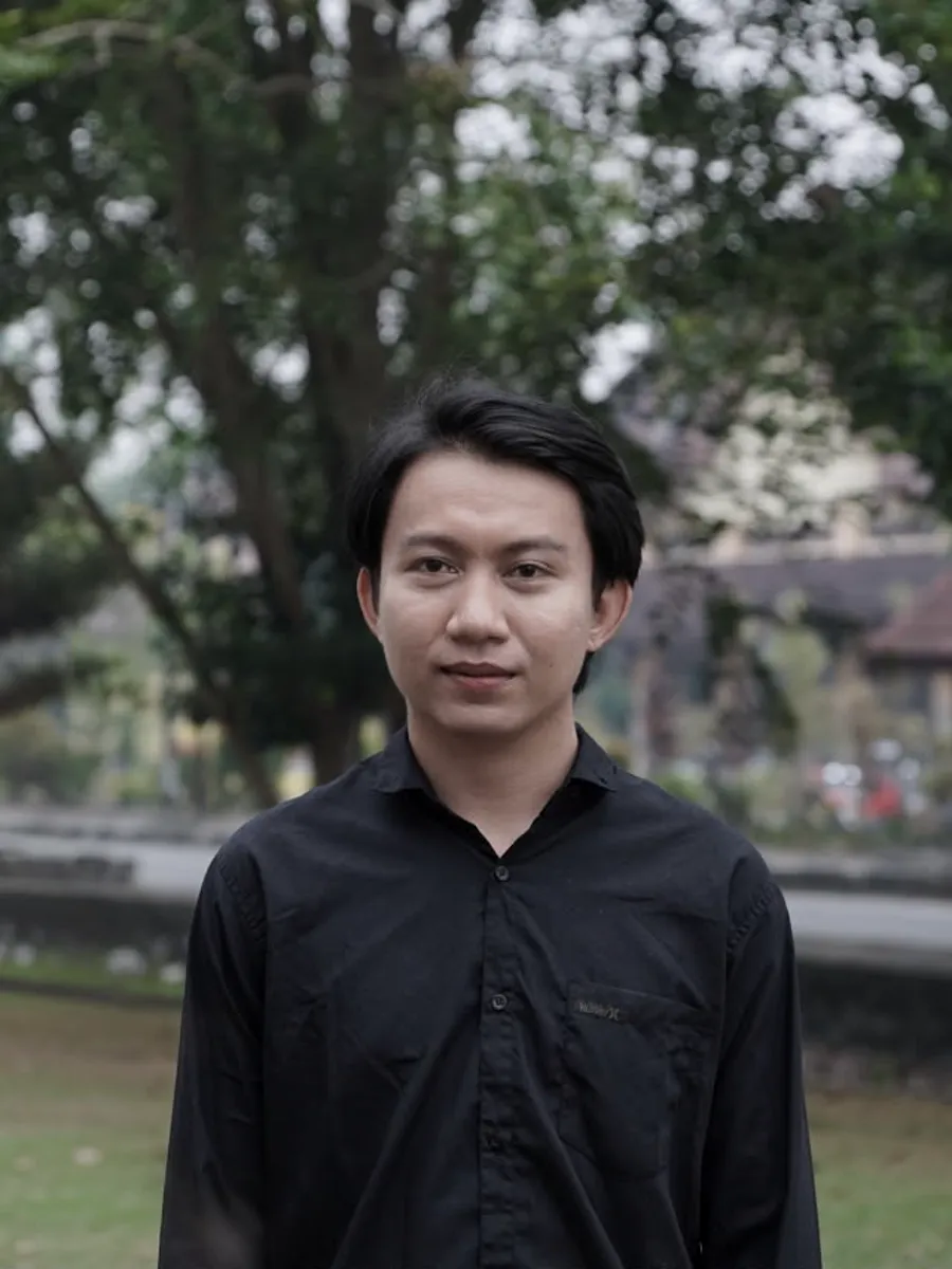 Andrew duduk bersandar di sofa hijau, mengenakan kaus hitam.