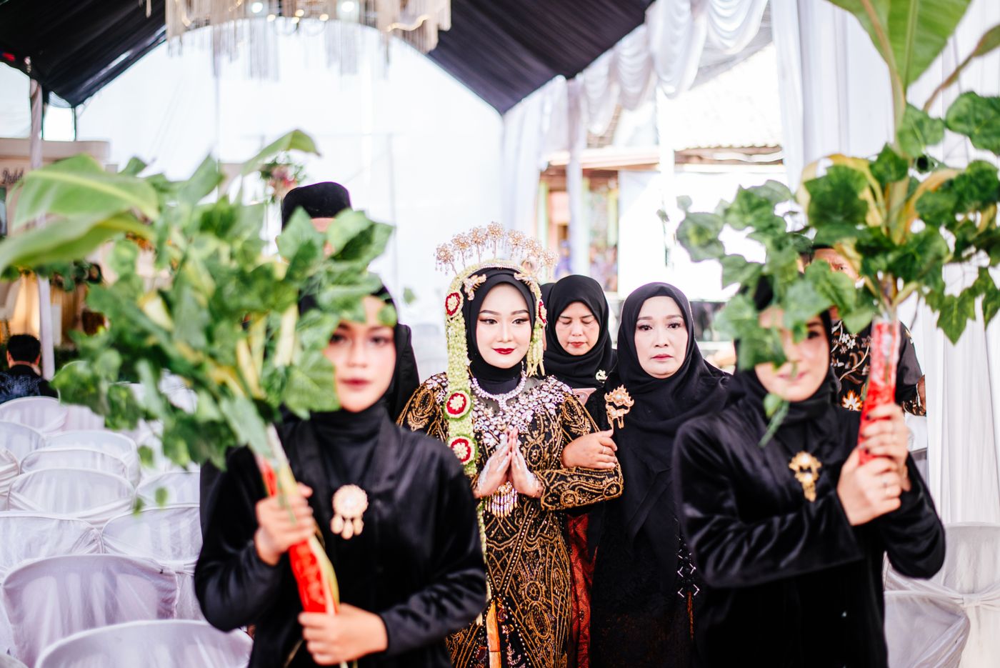 Iring-iringan pengantin membawa daun hijau