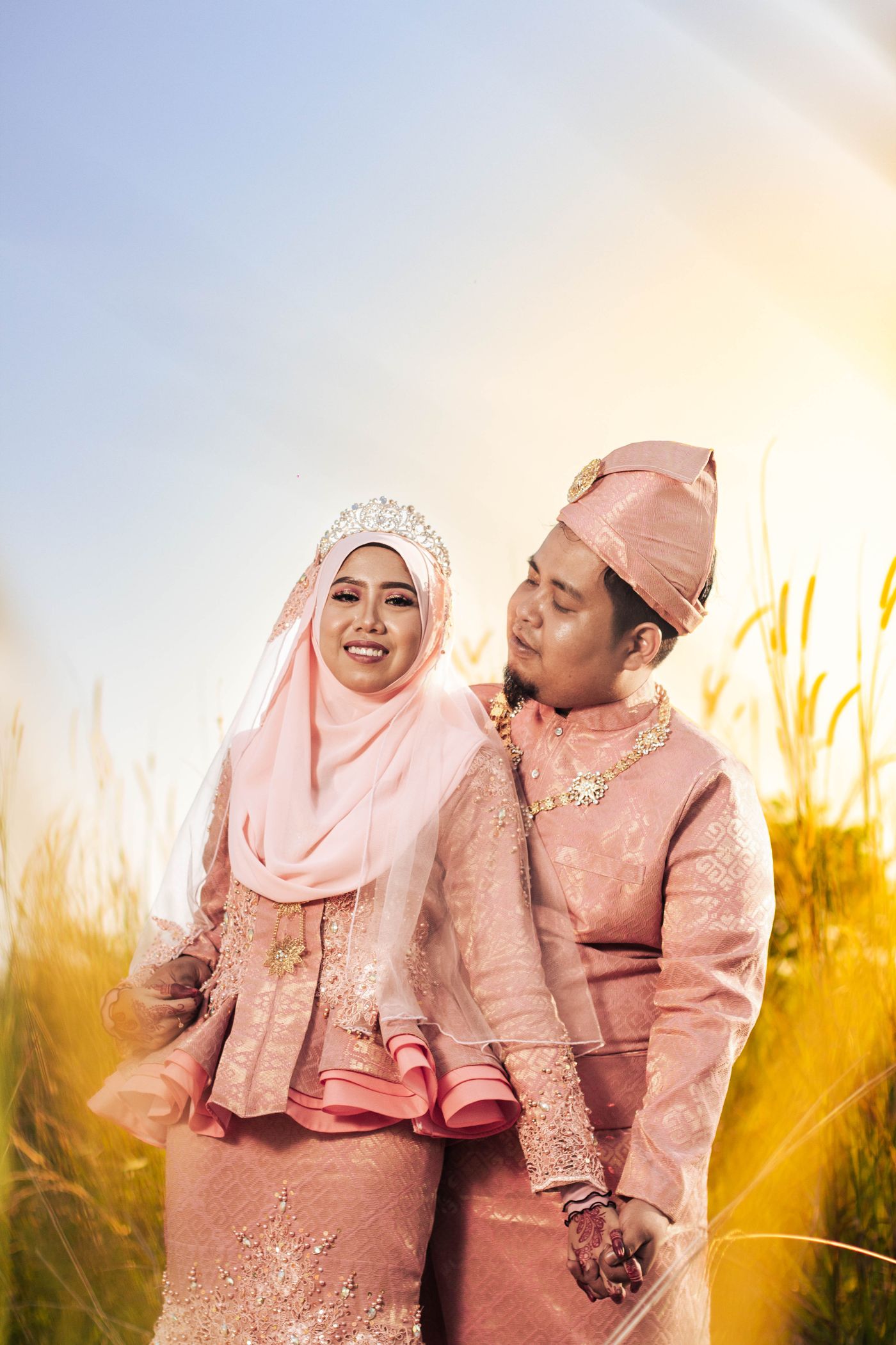 Pasangan berbusana merah muda di ladang saat senja