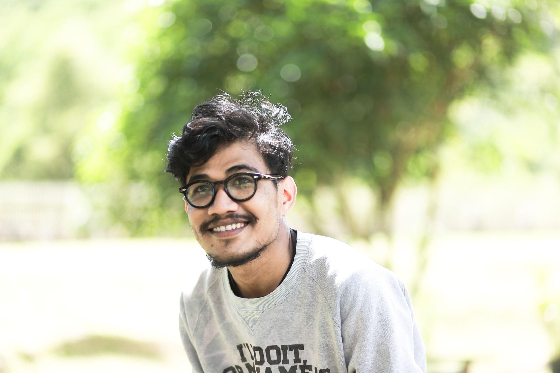 Bagas tersenyum, berkacamata