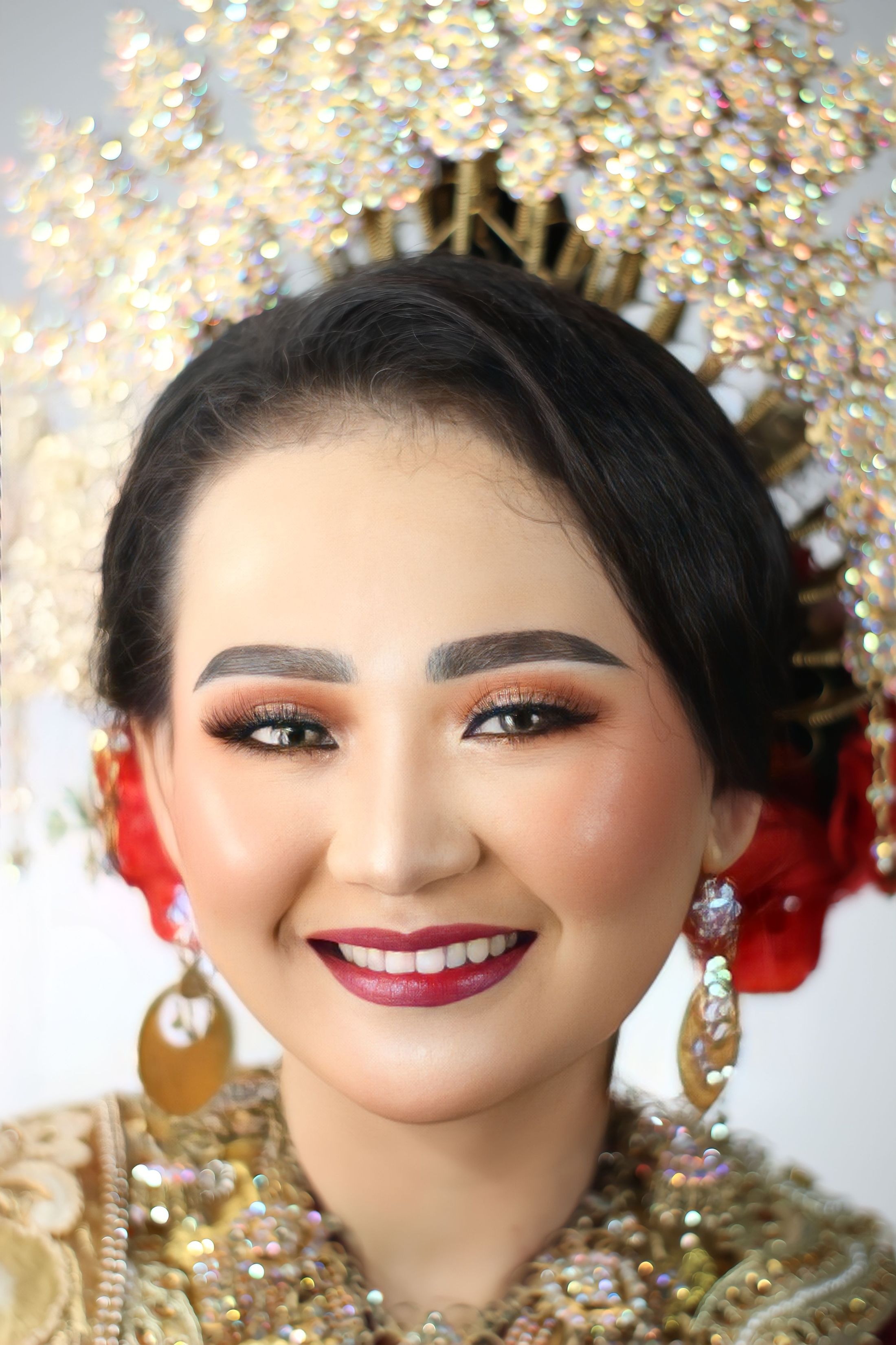 Pengantin tersenyum dengan hiasan kepala emas