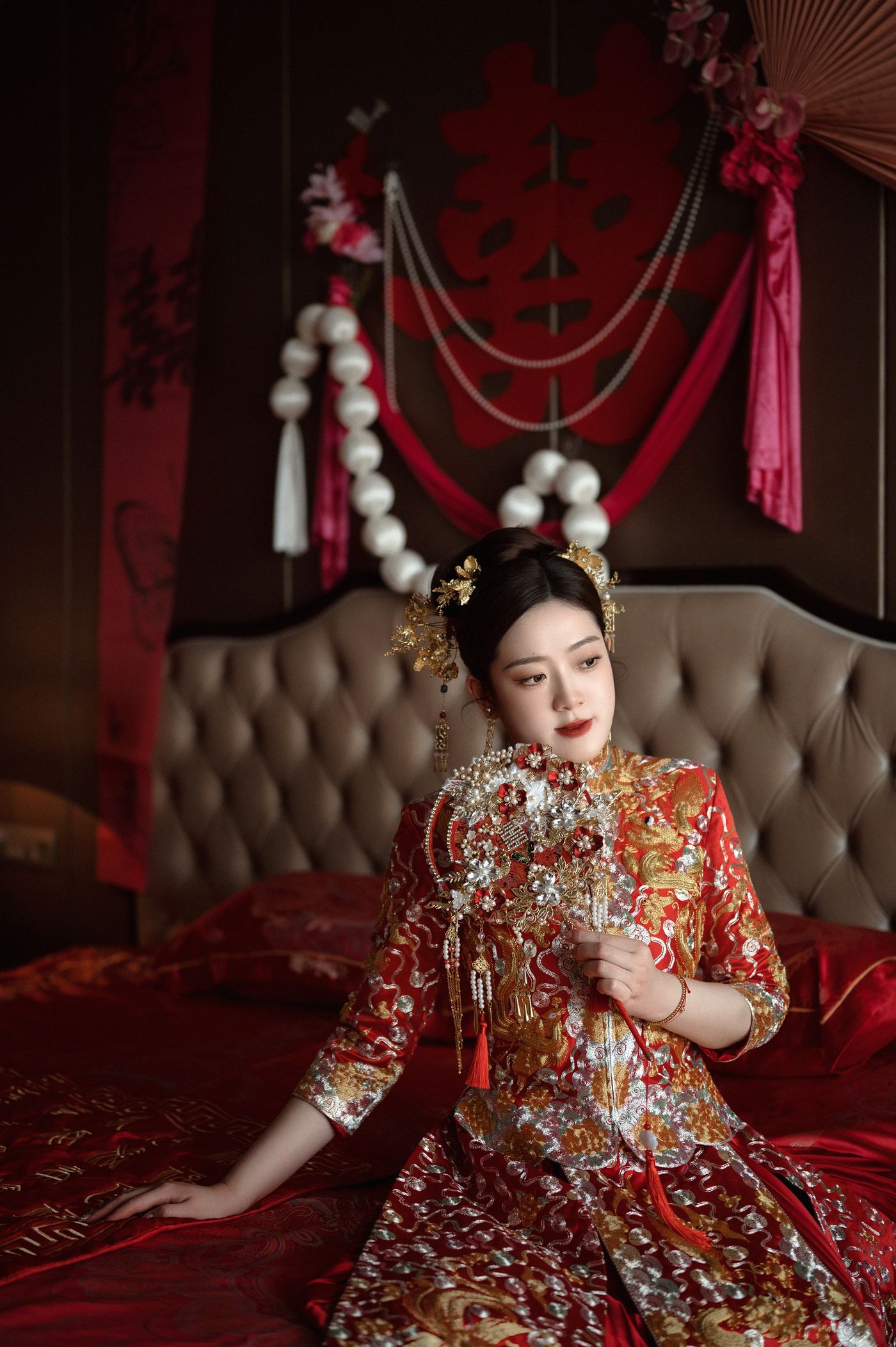 Pengantin perempuan berbusana sulam merah di atas ranjang berbalut kain merah