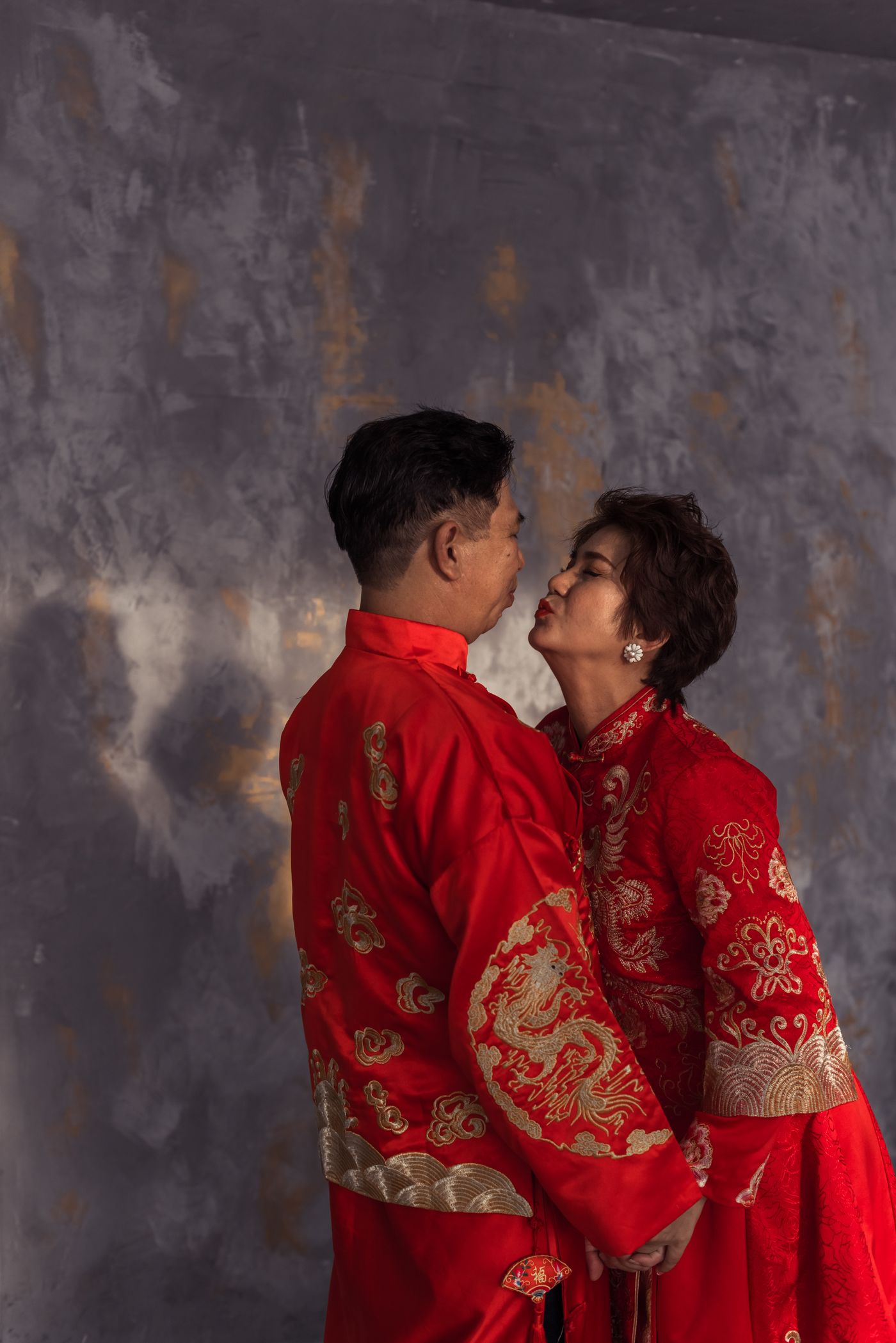 Pasangan berbusana pengantin merah saling berdekatan